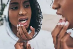 woman examines teeth in mirror